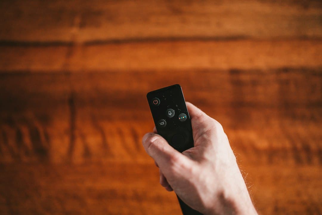 Main tenant une télécommande devant une télévision pour saisir un code